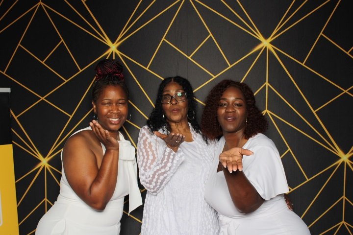 Three guests smiling in a photo booth at the Matthew and Pamela wedding
