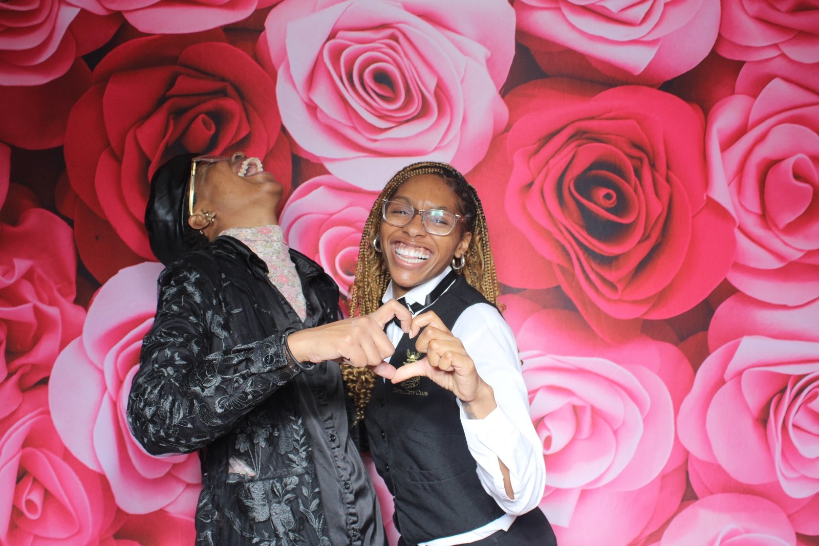 Guests laughing at a Valentine party against a rose wall