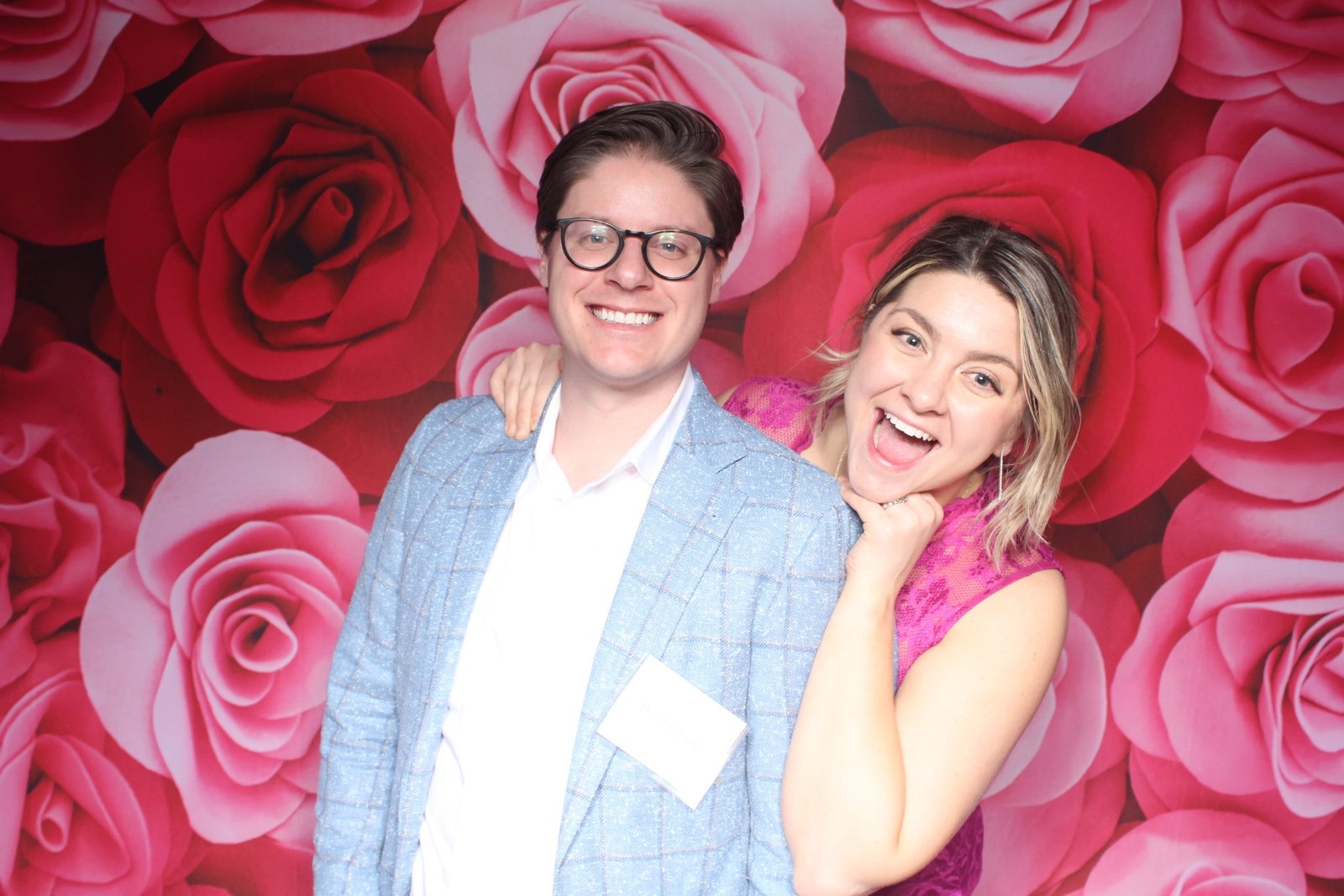 Guests smiling together in front of a red rose wall at a Valentine celebration